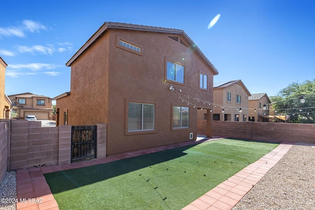 back of house featuring stucco siding, a yard, and a fenced backyard