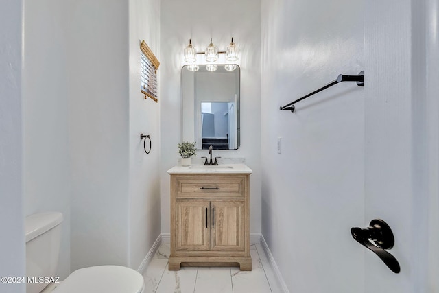 bathroom featuring toilet, vanity, and baseboards