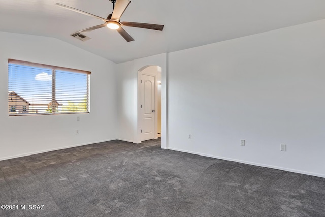 unfurnished room featuring visible vents, a ceiling fan, dark carpet, arched walkways, and vaulted ceiling