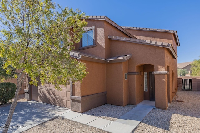 view of front of house featuring stucco siding, a garage, concrete driveway, and fence