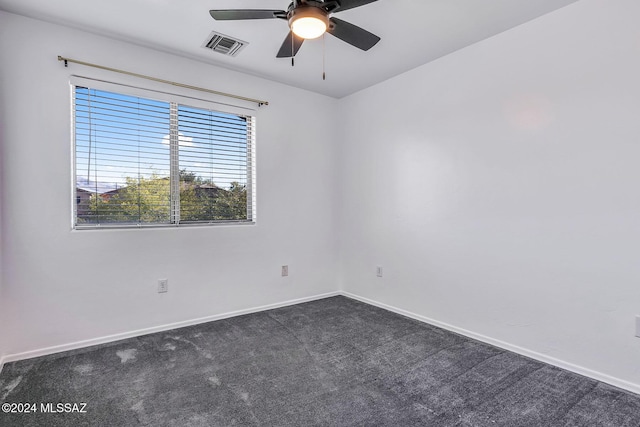 spare room with dark colored carpet, visible vents, baseboards, and ceiling fan