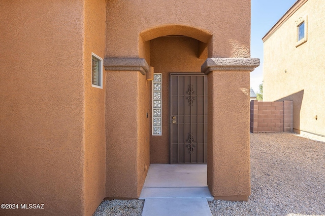 property entrance featuring fence and stucco siding