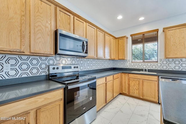 kitchen with a sink, stainless steel appliances, dark countertops, and marble finish floor