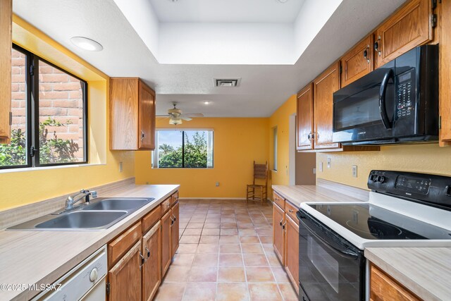 kitchen featuring a sink, black microwave, range with electric cooktop, light countertops, and visible vents