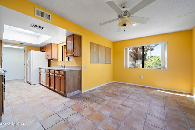 kitchen featuring visible vents, white appliances, a sink, and brown cabinets