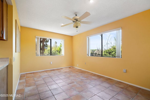 unfurnished room featuring light tile patterned flooring, a ceiling fan, and baseboards