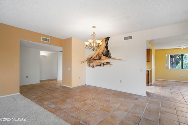 empty room with light tile patterned floors, visible vents, and ceiling fan with notable chandelier