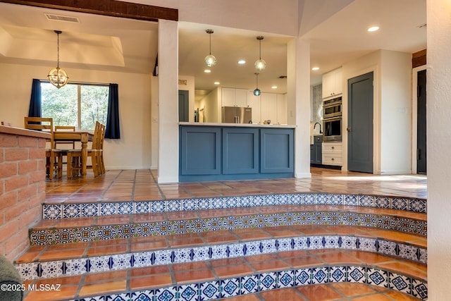 kitchen with visible vents, an inviting chandelier, a tray ceiling, stainless steel refrigerator, and tile patterned floors