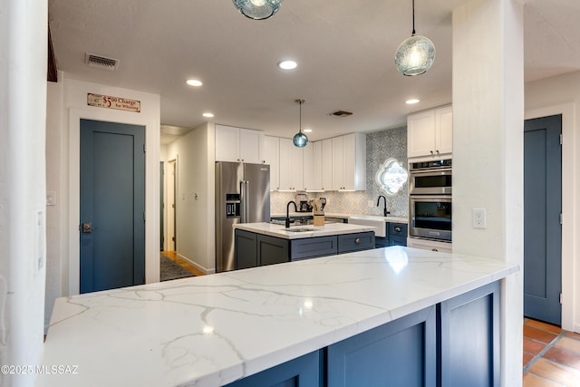 kitchen with a center island with sink, recessed lighting, a sink, decorative backsplash, and appliances with stainless steel finishes
