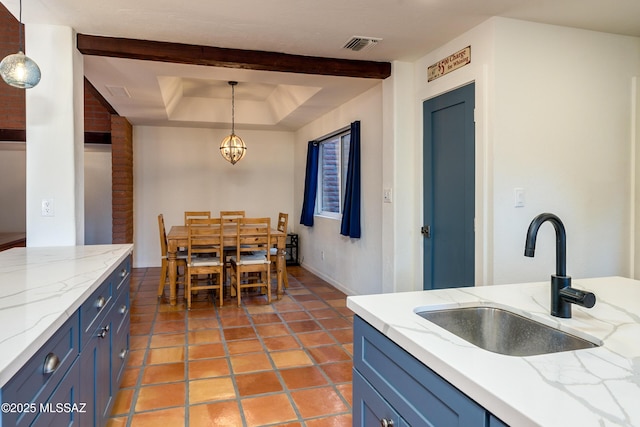 kitchen with visible vents, a sink, blue cabinetry, an inviting chandelier, and hanging light fixtures
