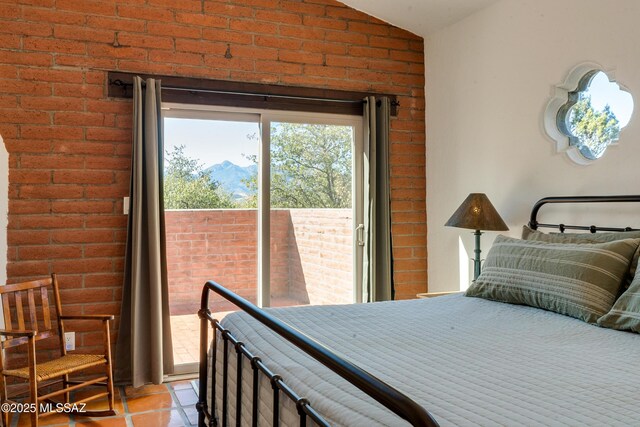bedroom featuring access to exterior, light tile patterned floors, brick wall, and vaulted ceiling