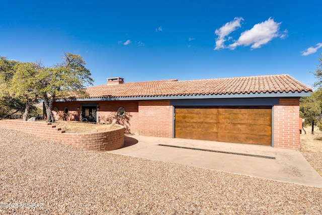 ranch-style house featuring brick siding, a chimney, and a tile roof