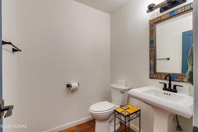 bathroom with tile patterned flooring, toilet, baseboards, and a sink