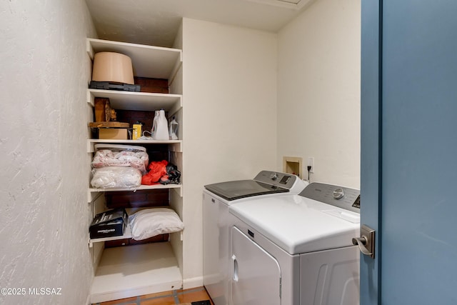 washroom with laundry area, washing machine and dryer, and a textured wall