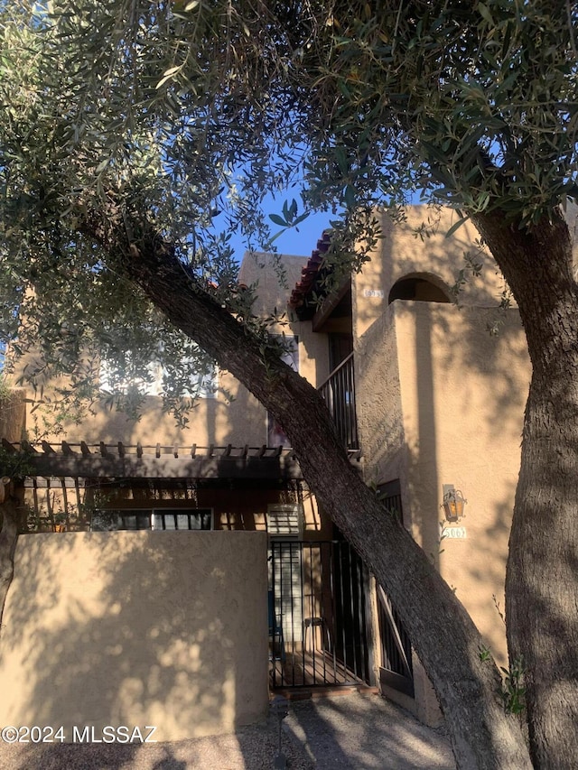 rear view of property with a gate, fence, and stucco siding