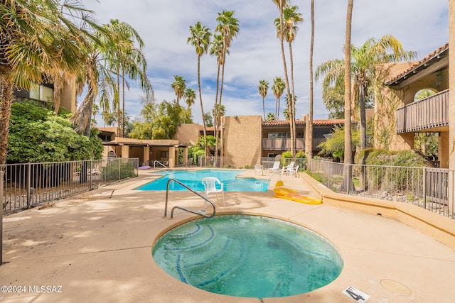 pool with a hot tub, a patio, and fence