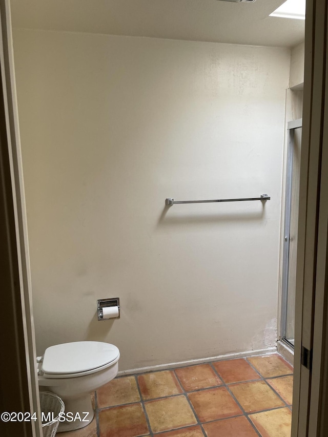 bathroom featuring tile patterned flooring, a stall shower, and toilet