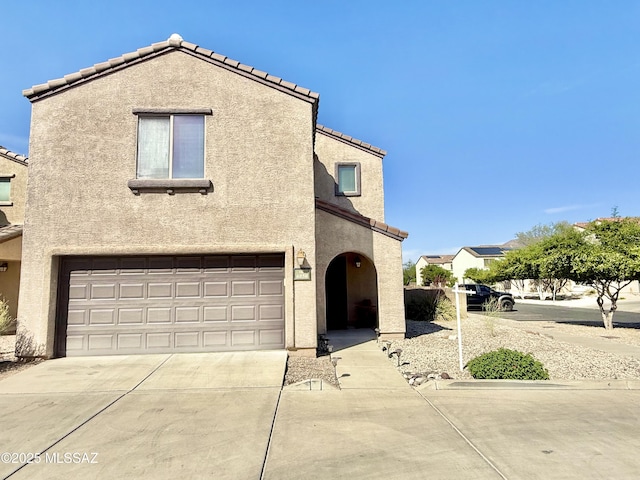 view of front of property with concrete driveway, an attached garage, a tiled roof, and stucco siding