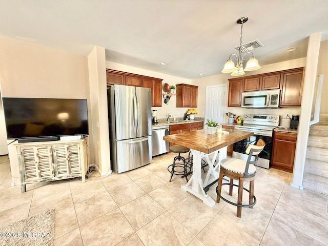 kitchen featuring an inviting chandelier, light tile patterned floors, decorative light fixtures, visible vents, and stainless steel appliances