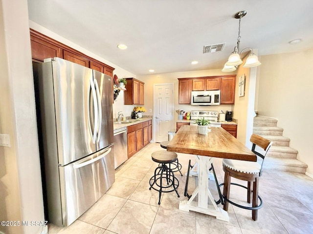 kitchen with visible vents, light countertops, appliances with stainless steel finishes, pendant lighting, and light tile patterned flooring