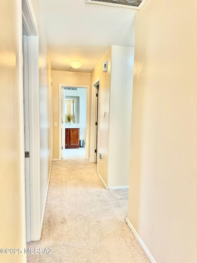 hall featuring carpet flooring, visible vents, and baseboards