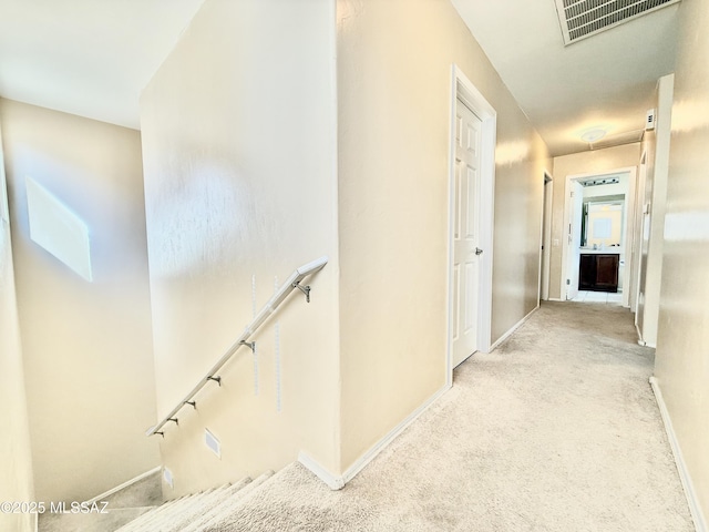 corridor featuring visible vents, baseboards, and carpet