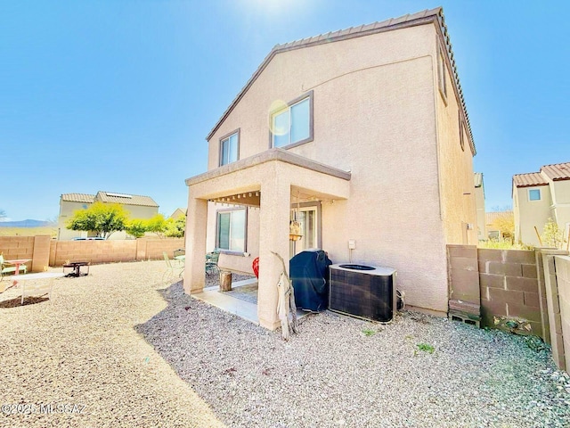 rear view of house with central air condition unit, a fenced backyard, stucco siding, and a patio area