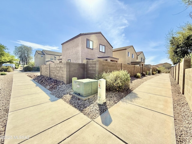 view of home's exterior featuring a residential view, stucco siding, fence private yard, and a tiled roof