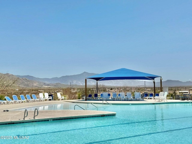 community pool with fence, a patio area, and a mountain view
