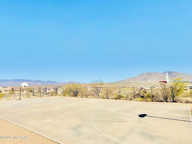view of basketball court featuring community basketball court, a mountain view, and fence