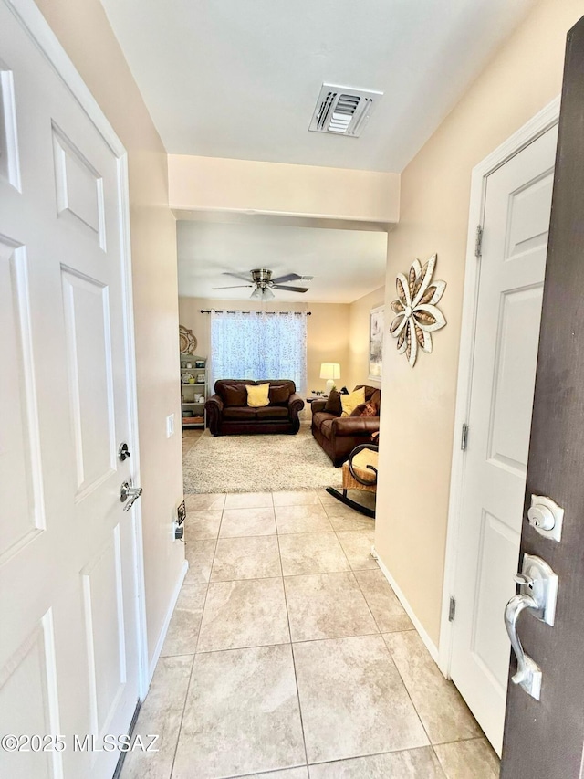 foyer entrance with baseboards, light tile patterned floors, ceiling fan, and visible vents