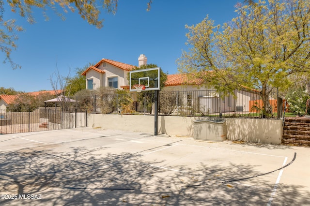 view of basketball court featuring fence and basketball hoop