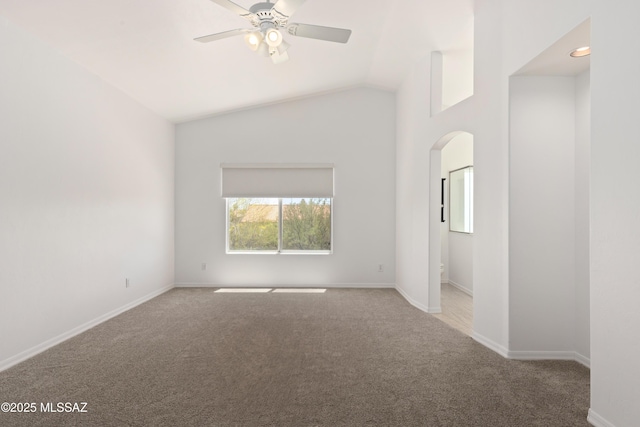 unfurnished room featuring carpet flooring, arched walkways, a ceiling fan, baseboards, and lofted ceiling