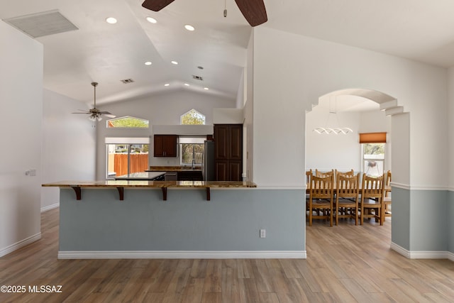 kitchen with recessed lighting, arched walkways, ceiling fan, and a kitchen bar