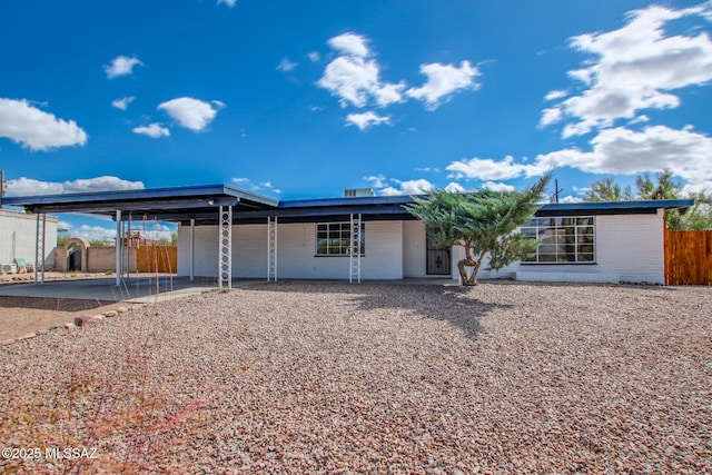 back of property featuring an attached carport, driveway, and fence