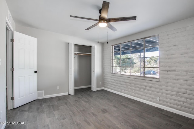 unfurnished bedroom featuring wood finished floors, visible vents, baseboards, ceiling fan, and a closet