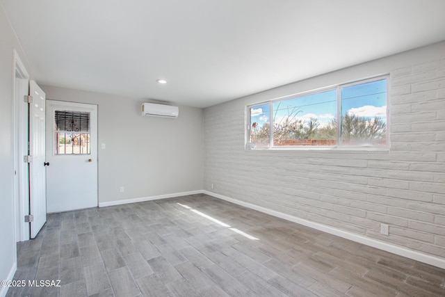 interior space with brick wall, baseboards, a wall mounted air conditioner, recessed lighting, and wood finished floors
