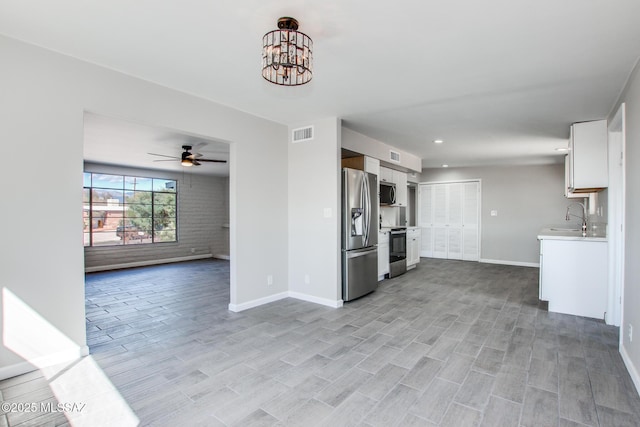 kitchen with baseboards, open floor plan, light countertops, ceiling fan with notable chandelier, and stainless steel appliances
