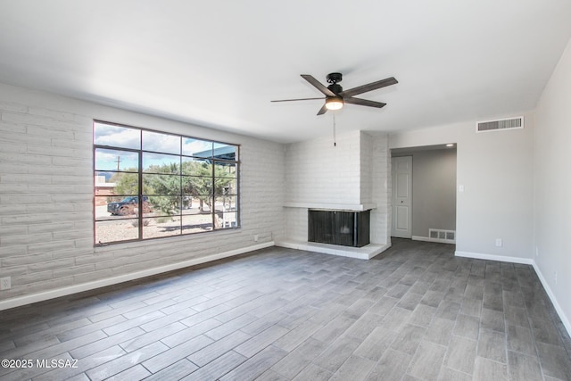 unfurnished living room with wood finished floors, a fireplace, visible vents, and ceiling fan