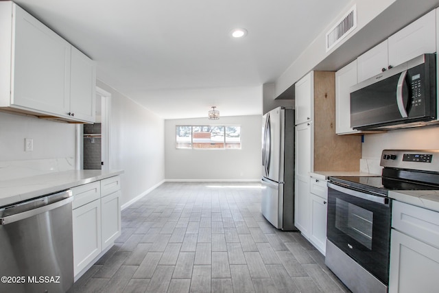 kitchen with stainless steel appliances, baseboards, visible vents, and white cabinetry