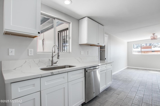 kitchen with light stone countertops, baseboards, white cabinetry, a sink, and dishwasher