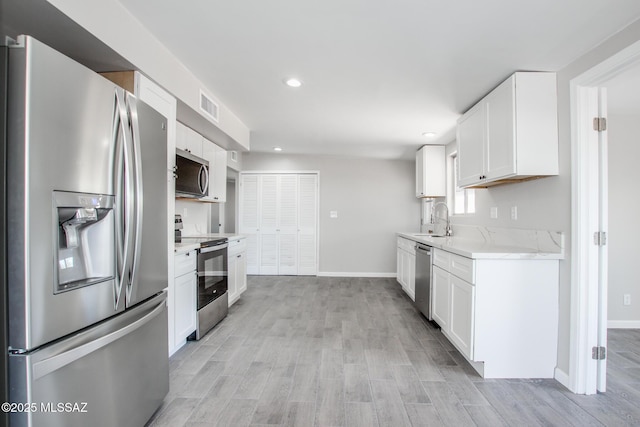 kitchen with visible vents, light countertops, appliances with stainless steel finishes, light wood-style floors, and a sink