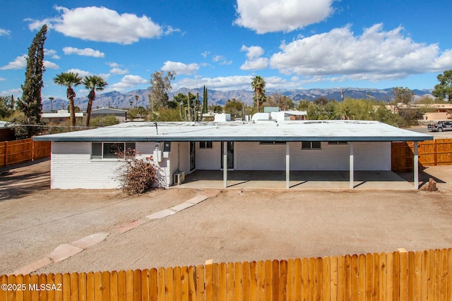 rear view of house with a mountain view, brick siding, a patio area, and fence