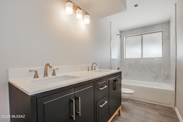 bathroom with double vanity, toilet, wood finished floors, and a sink