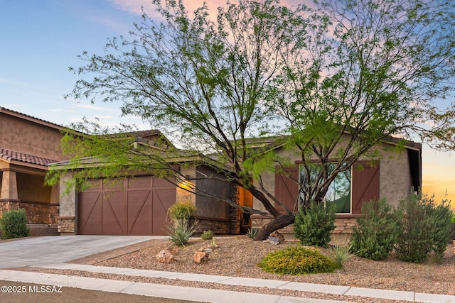 view of front of property with concrete driveway, a garage, stone siding, and stucco siding