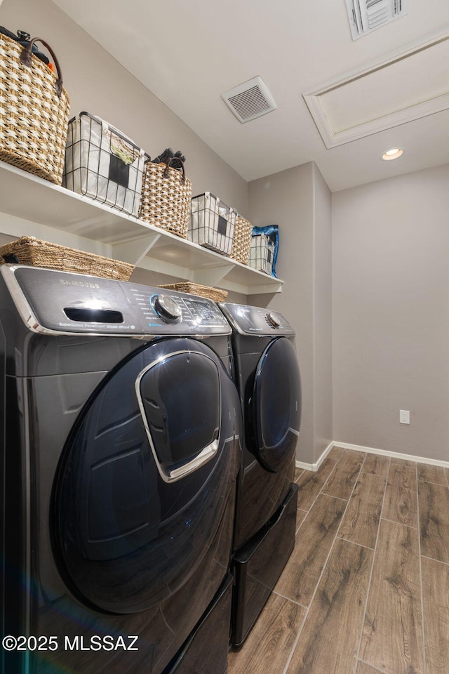 clothes washing area featuring washer and dryer, visible vents, dark wood finished floors, and laundry area