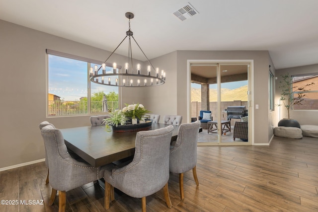 dining area with visible vents, baseboards, an inviting chandelier, and wood finished floors