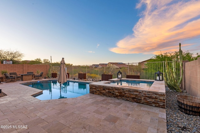 pool at dusk with a patio area, a fenced in pool, an in ground hot tub, and a fenced backyard