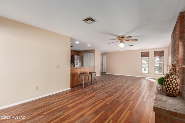 unfurnished living room featuring dark wood finished floors, baseboards, visible vents, and ceiling fan