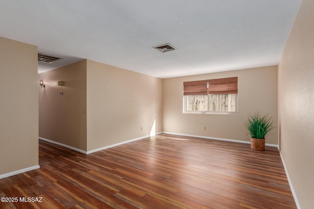 unfurnished room with visible vents, baseboards, and wood finished floors